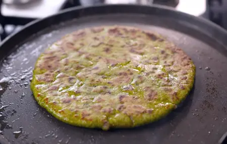 Cooking aloo methi parathas on a tawa