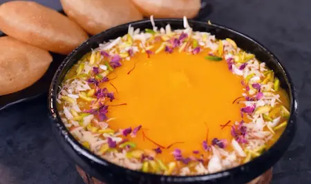Aamras Puri served with garnished aamras and hot pooris