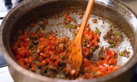 Cooking tomatoes and dry spices in pan for the Methi Chaman gravy