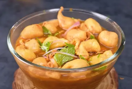 Assembling pani phulki with soaked phulkis, spicy water, onions and herbs