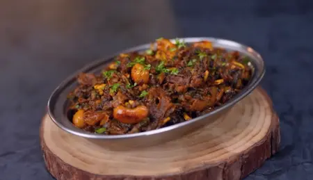 Final garnishing of Karela Pyaz Ki Sabji with sugar, amchur and coriander