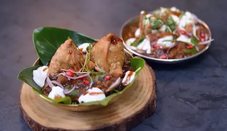 Plating and garnishing samosa chaat with chutneys and toppings