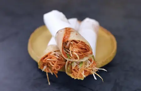 Crispy and spicy street style noodle frankie served hot, wrapped in butter paper