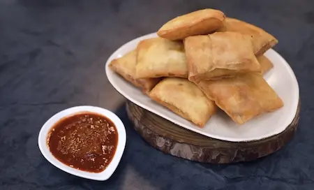 Crispy Chinese Pocket Samosas served with Schezwan chutney on a plate