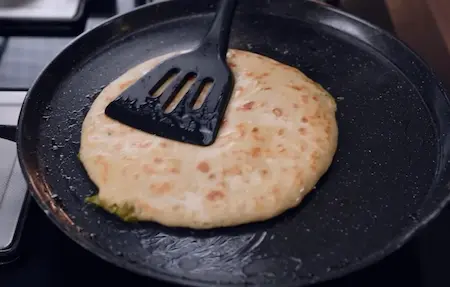 Step 5: cooking Green Garlic and Matar Paratha on tawa with butter