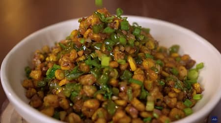 Crispy corn tossed with vegetables, ready to be served, garnished with spring onions and coriander.