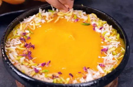 Garnished aamras with nuts, rose petals, and saffron strands