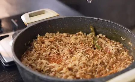 Soaked rice added to the dal mixture with water, mint, and coriander, cooking in a covered pot