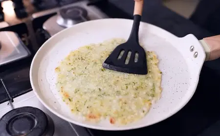 Cooking sabudana thalipeeth on a hot pan until golden and crispy