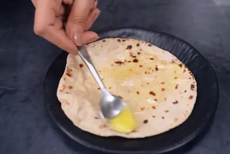 Soft phulkas being rolled and cooked on tawa for serving with Aloo Kali Mirch