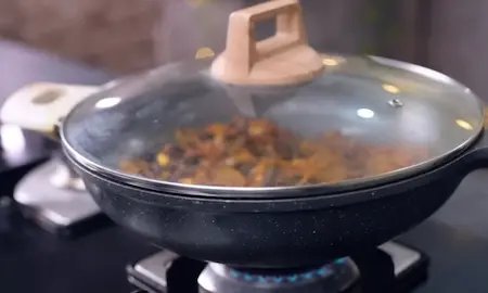 Karela and onions cooking covered to blend flavors for Karela Pyaz Ki Sabji