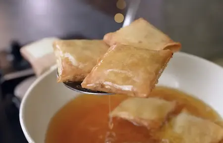 Golden brown Chinese Pocket Samosas being deep fried to crispy perfection