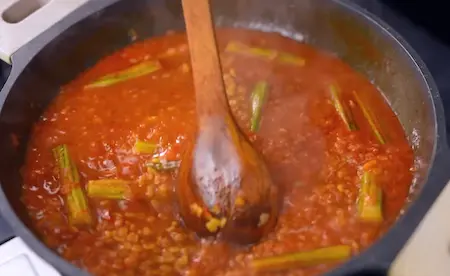 Adding moringa pieces to the dal