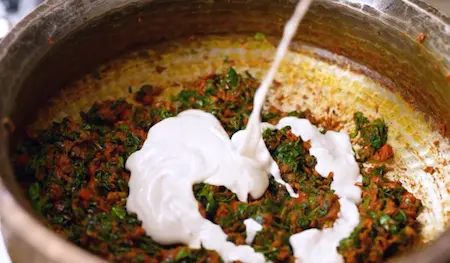 Cashew paste mixing into methi gravy for creamy Methi Chaman curry