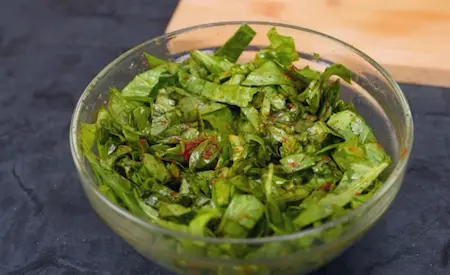 Seasoned chopped spinach being squeezed to remove excess water for stuffing parathas