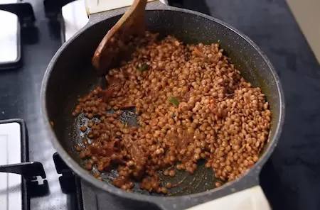 Whisked curd being mixed into the masala followed by soaked masoor dal in a pot