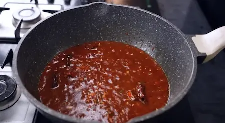 Spicy red sauce with chilli paste, ketchup and soya sauce simmering in wok