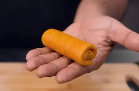 Rolling and stuffing the sambar vadi like a spring roll with flavorful coconut filling