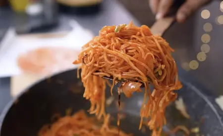 Schezwan noodles being tossed with cabbage, capsicum, onion and spicy schezwan chutney