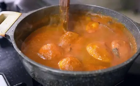 Adding water and tomato puree to the masala for Punjabi Dum Aloo