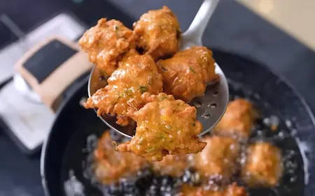 Frying Crispy Corn Pakoda in hot oil until golden brown and crunchy