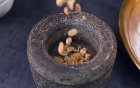 Crushed peanuts and melted ghee being mixed into the ingredients for maddur vade recipe