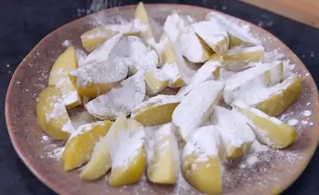 Coating boiled potato wedges with cornflour for crispiness in Goan Chilli Potato