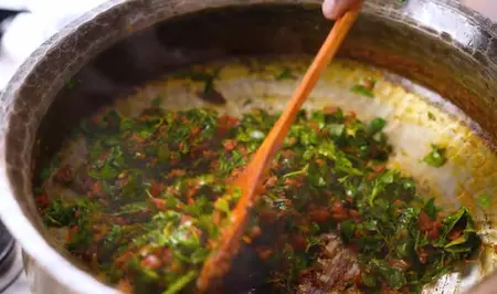 Fresh chopped methi cooking in masala base in pan for Methi Chaman recipe