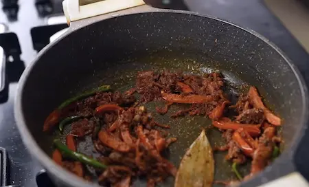 Tomatoes and ground spices being cooked until oil separates for Masoor Dal Pulao masala