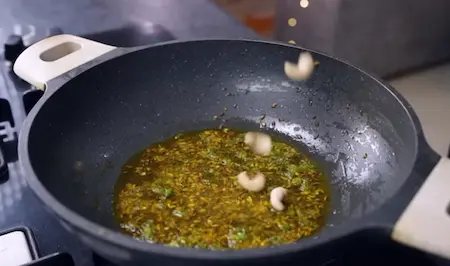 Tempering cumin, fennel, mustard seeds with green chillies and cashews for Karela Pyaz Ki Sabji