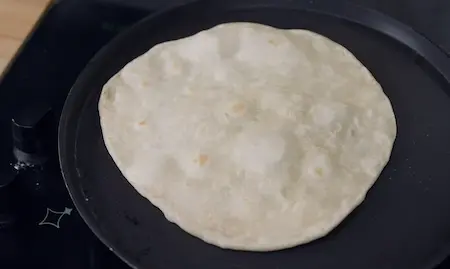 Half-cooked frankie roti being prepared on a tawa for street style wrap