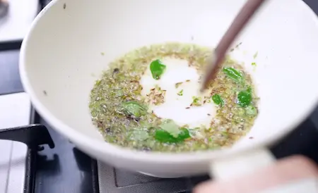 tempering cumin, fennel, cloves, green chilli, curry leaves in oil for bhutte ka khees