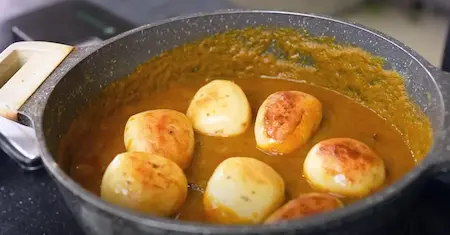 Coating fried potatoes with masala for Punjabi Dum Aloo