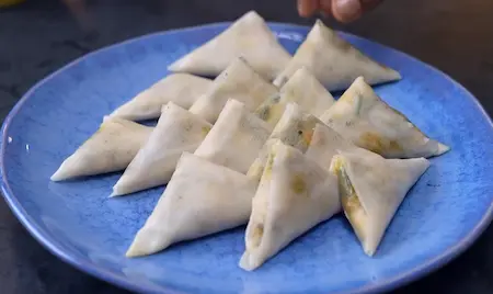 Folding and shaping patti samosas with cheesy corn spinach filling for Cheesy Corn Palak Samosa Recipe
