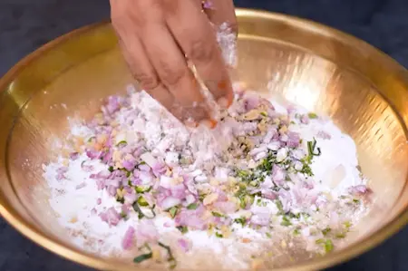 Adding chopped green chillies, ginger, curry leaves, coriander, and onion to the dry mix for maddur vade recipe