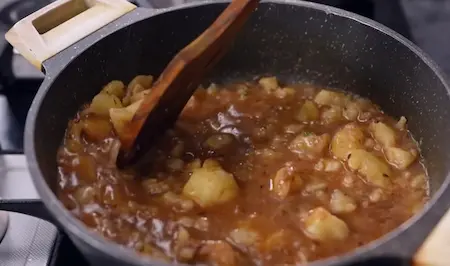 Dum Aloo Ki Sabzi simmering in a pan with thick gravy