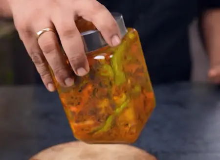 Mixing carrot, radish and green chilli with Indian pickle spices and pouring hot mustard oil