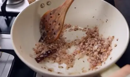 Onions, garlic, and ginger sautéing in oil as the base for Chatpata Lauki Masala gravy.