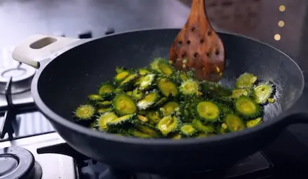 Karela being fried until golden brown in mustard oil for Karela Pyaz Ki Sabji