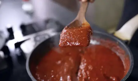 Making street style Schezwan sauce with garlic, ginger, red chilli paste and spices in a pan