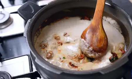 Adding and sautéing the coconut masala paste into the curry base for rich flavour