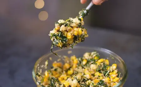 Mixing grated cheese into cooled corn and spinach mixture for Cheesy Corn Palak Samosa Recipe
