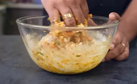 Mixing corn, spices, herbs, and besan together to prepare Crispy Corn Pakoda batter