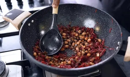 Adding spice mix, peanuts, and dry coconut to beetroot-carrot mixture