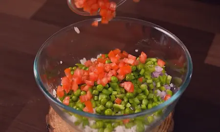 Step 2: Adding chopped onion, capsicum, tomatoes and green peas to poha for Easy 10-Minute Poha Snack