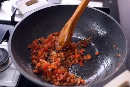 Cooking cumin seeds, garlic, ginger, onions, green chilies, and tomatoes