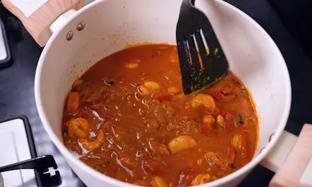 Assembling the prawn biryani with masala and rice.