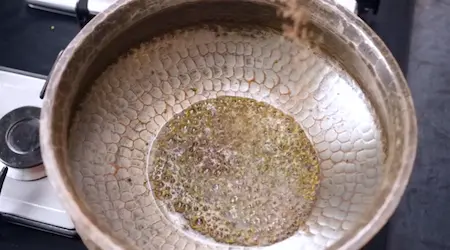 Hot oil with fennel seeds and cumin sizzling in a pan for Methi Chaman tadka