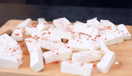Paneer cubes being marinated with chilli powder and salt for crispy paneer recipe