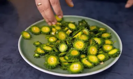Sliced karela with salt and turmeric resting to remove bitterness for Karela Pyaz Ki Sabji